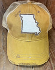 Front view of a yellow and tan mesh-back trucker hat with a distressed finish. A white patch on the front features the outline of the state of Missouri.