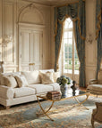French country living room with cream sofa, antique-style chairs, gold coffee table, blue drapes, and classic European details.